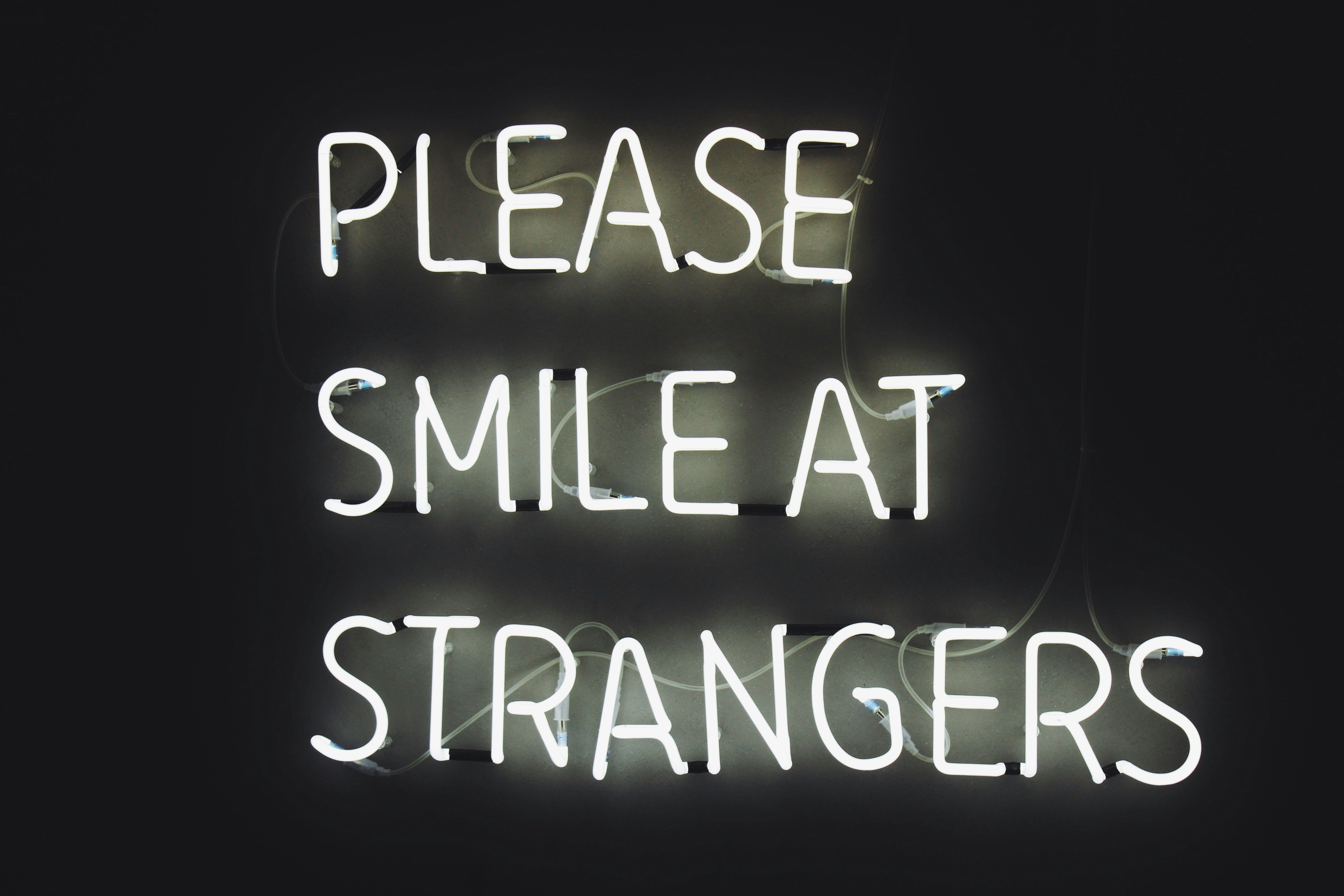 'Please smile at strangers' in neon lights (Unsplash: Haut Risque)