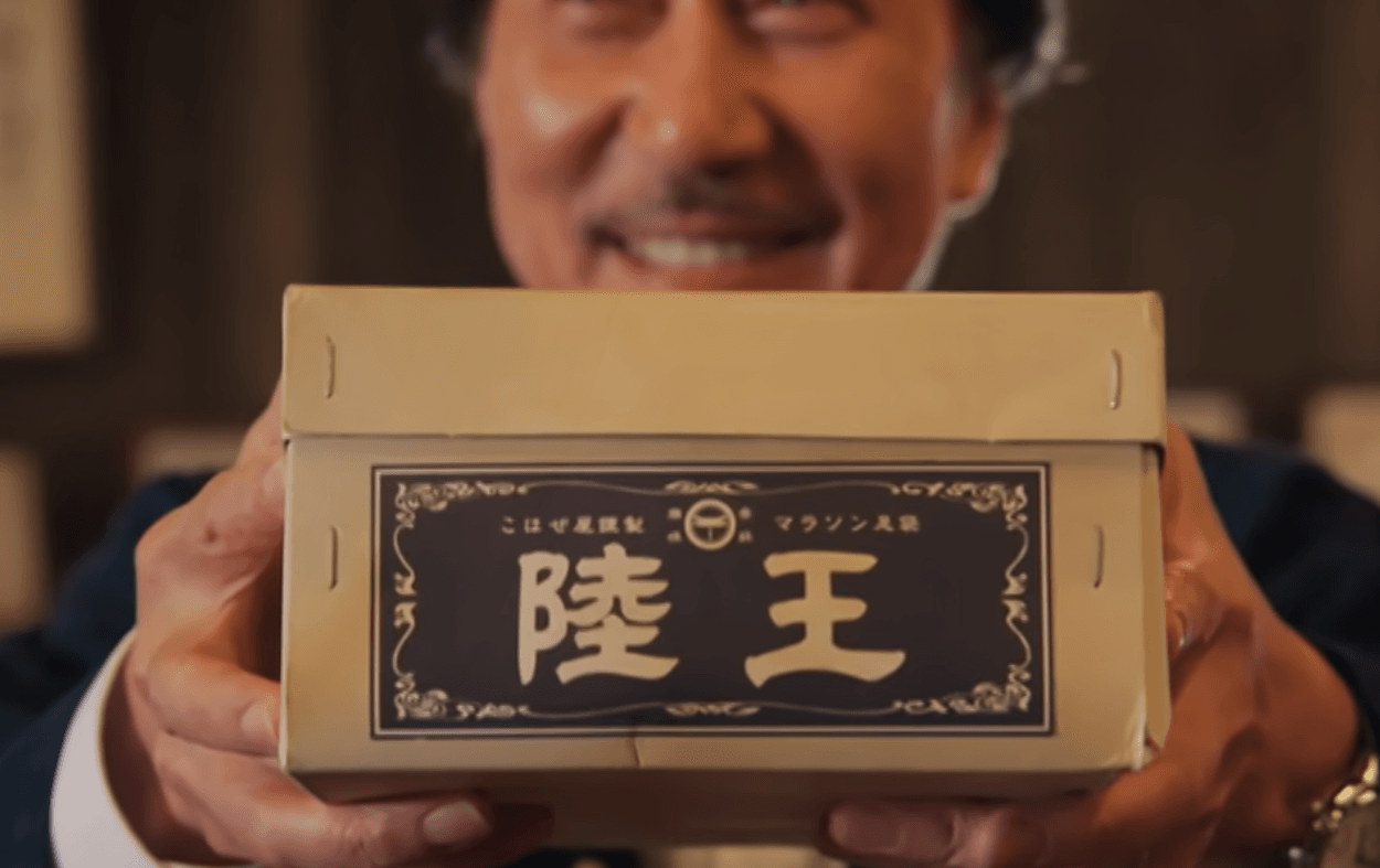 A character from the j-drama Rikuoh holding up a box that has Rikuoh written on it in kanji