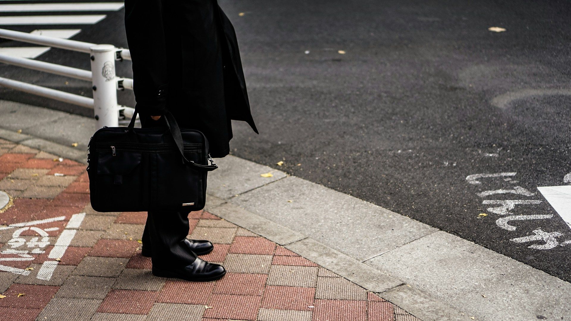 A Japanese salaryman standing on the streetcorner with his suit and suitcase, about to head to the office, where he'll need to use business Japanese