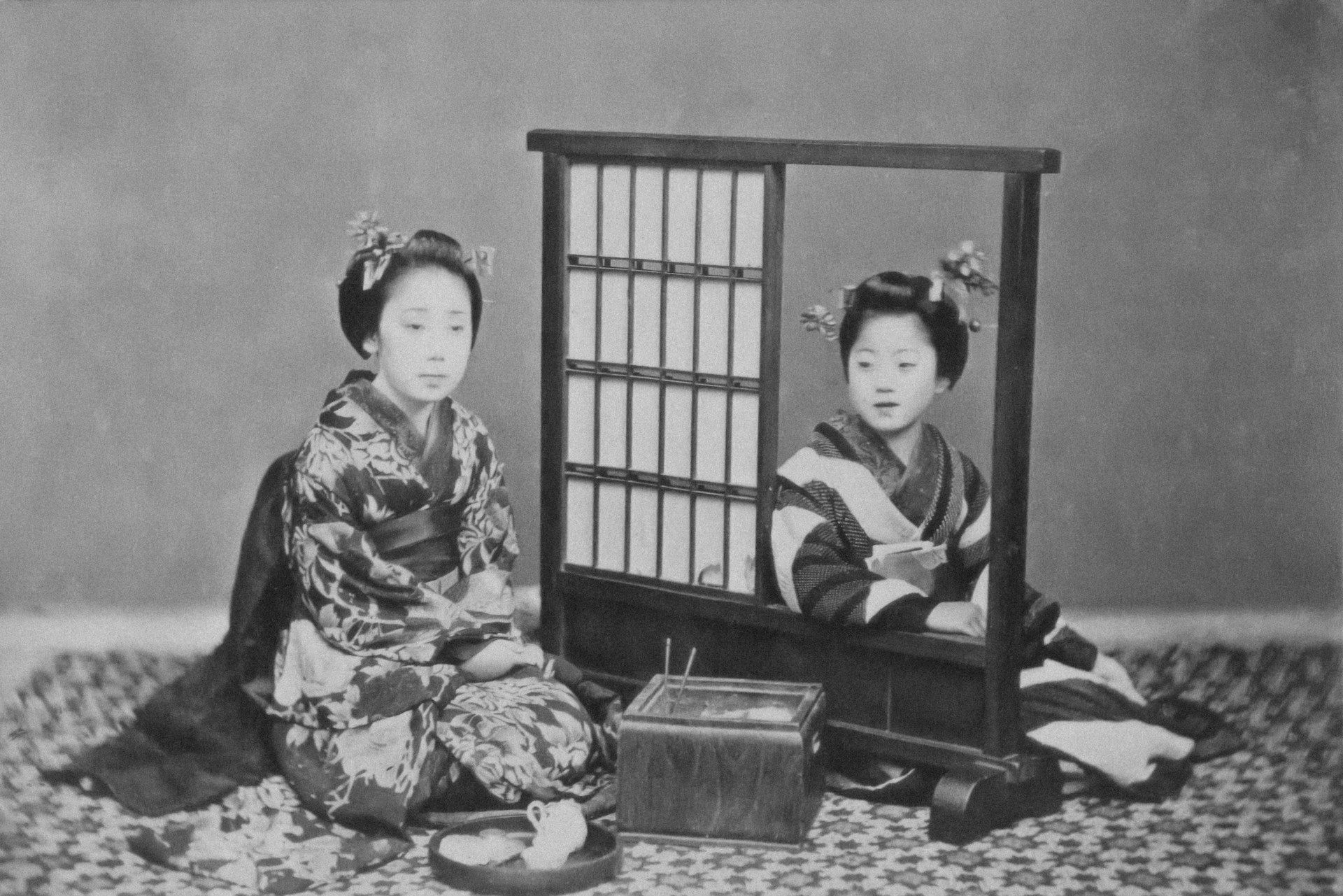 An old photo of two Japanese women in kimonos sitting next to each other