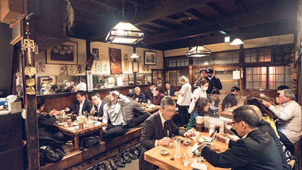A photograph of several people seated at a traditional Japanese pub