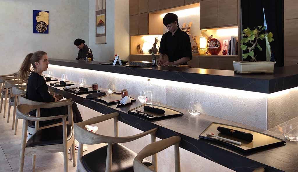 A photograph of chefs and a guest at a sushi bar
