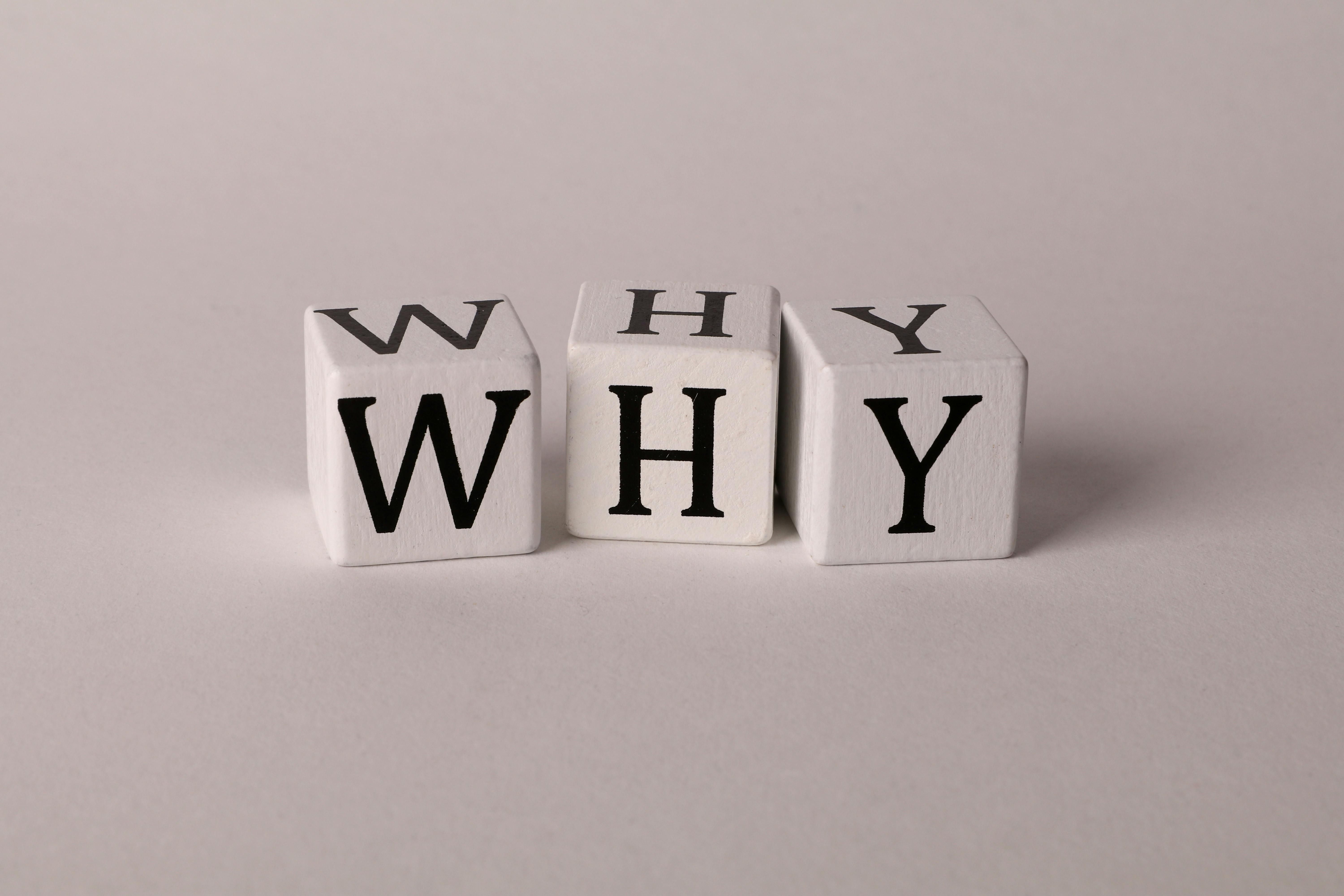 Three wooden blocks that spell out 'why', because por qué means why in Spanish